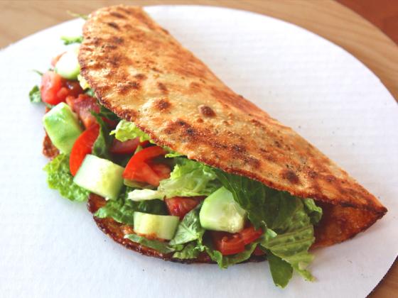 Folded pizza served with fresh salad